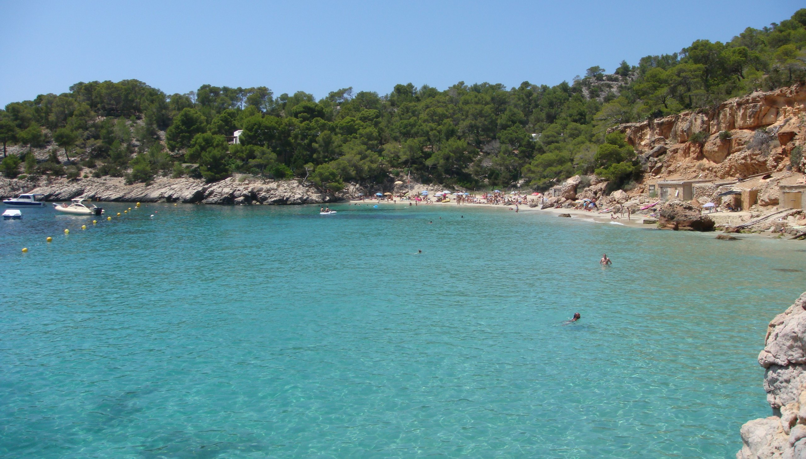 Cala Salada Ibiza: vissersbaai aan de rand van Es Amunts, met Cala Saladeta en de toegang in 2026 1 De baai van Cala Salada met turquoise water, pijnbos op de heuvels en vissershuisjes onder de rode rotswand