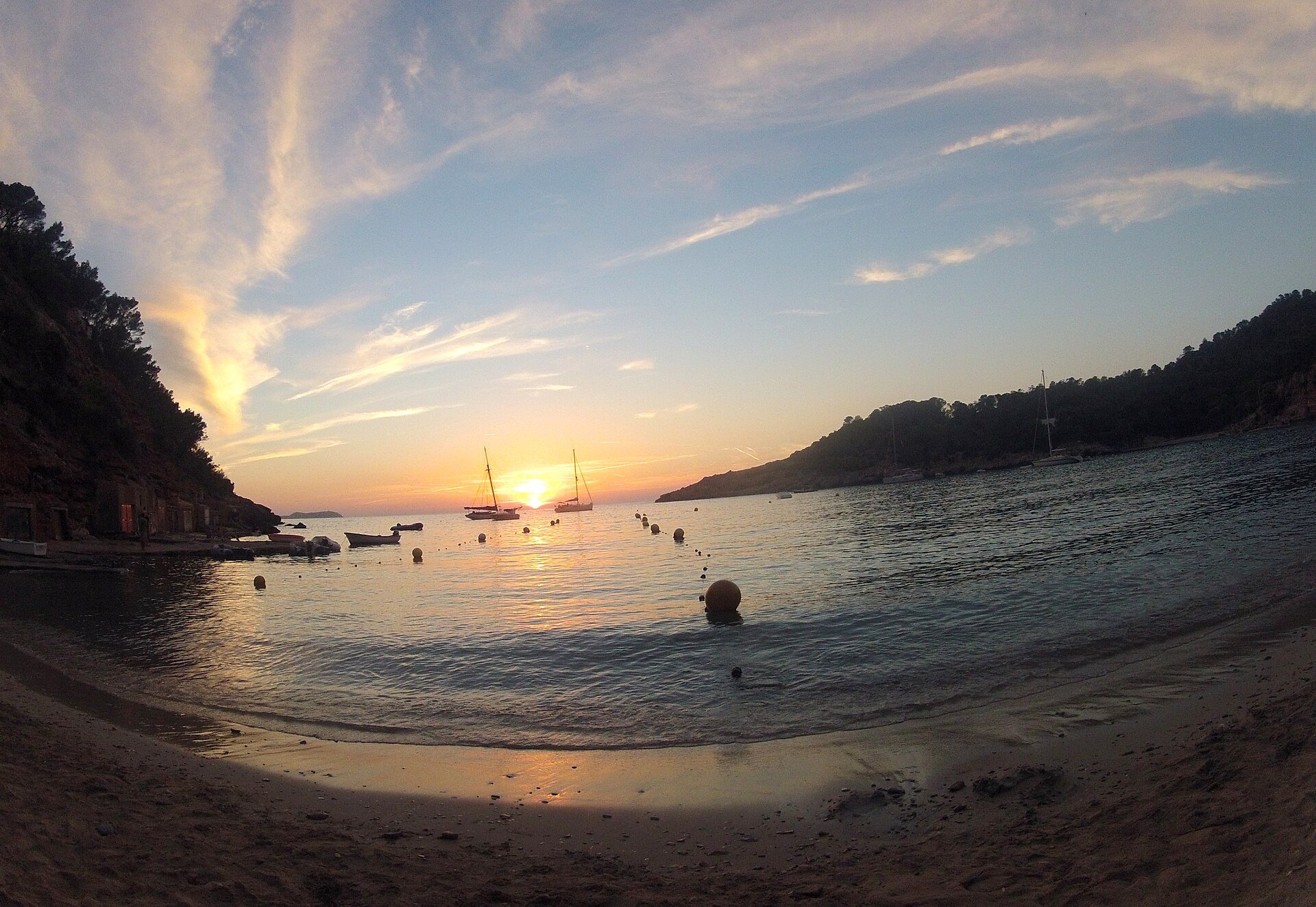 Cala Salada Ibiza: vissersbaai aan de rand van Es Amunts, met Cala Saladeta en de toegang in 2026 4 Zonsondergang boven zee, gezien vanaf de zandige waterrand van Cala Salada