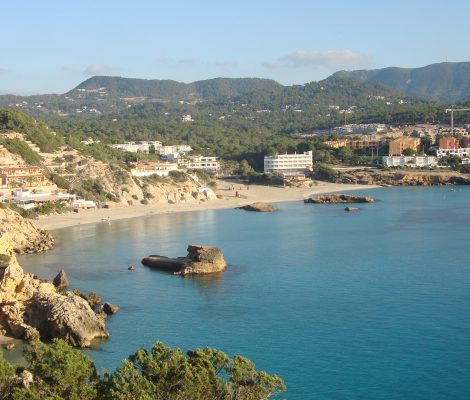 De baai van Cala Tarida aan de westkust van Ibiza met het eilandje in het turquoise water en de hotels op de heuvels