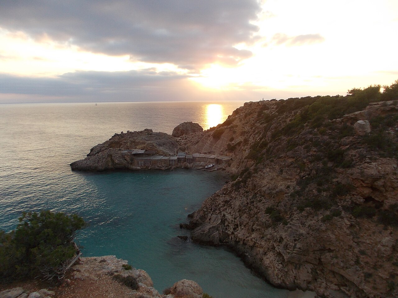 Cala Tarida Ibiza: het strand, de bussen A1 en P9 en parkeren 8 Zonsondergang boven zee bij Cala Tarida op Ibiza, met de rotspunt en het turquoise water van de inham op de voorgrond