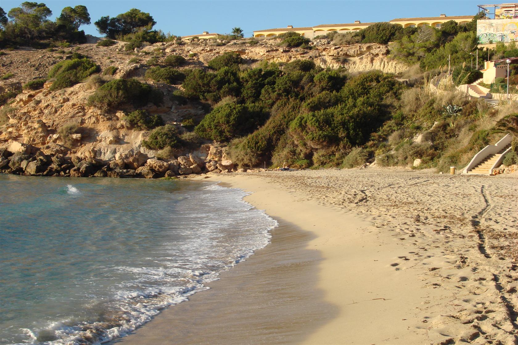 Cala Tarida Ibiza: het strand, de bussen A1 en P9 en parkeren 2 Het brede zandstrand van Cala Tarida op Ibiza met rotsen en begroeide heuvels aan de rand van de baai