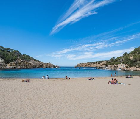 Het zandstrand van Cala Vadella op Ibiza met de beschutte baai en beboste kliffen