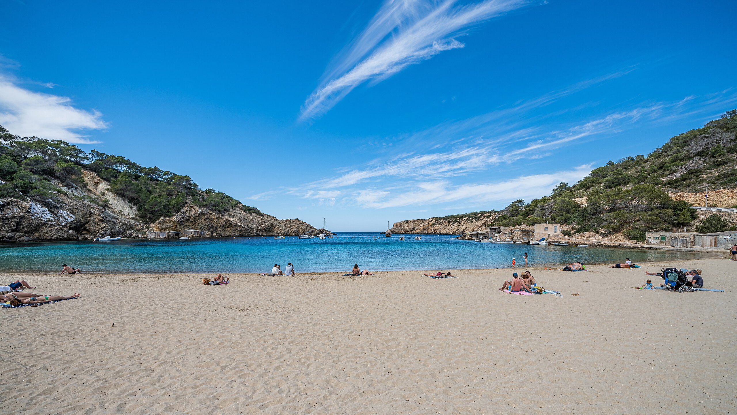 Het zandstrand van Cala Vadella op Ibiza met de beschutte baai en beboste kliffen