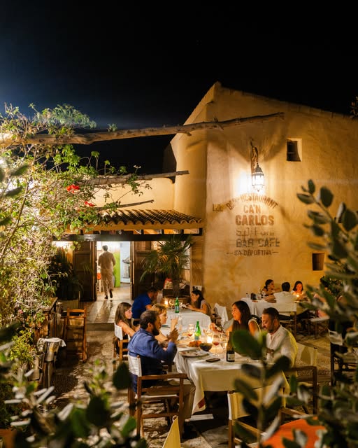 De verlichte tuin en finca van Can Carlos in de avond