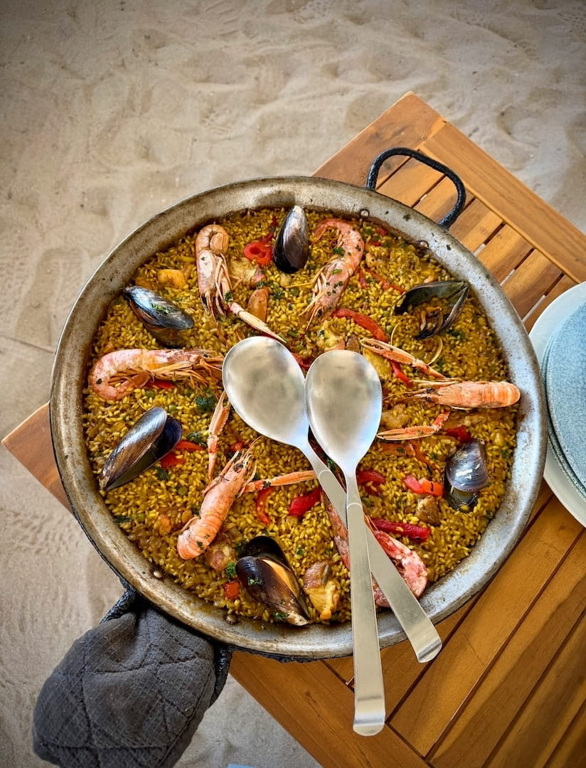 Can Gavella Mallorca: de chiringuito op het zand van Playa de Muro 3 Paella met zeevruchten in een pan op het strand bij Can Gavella