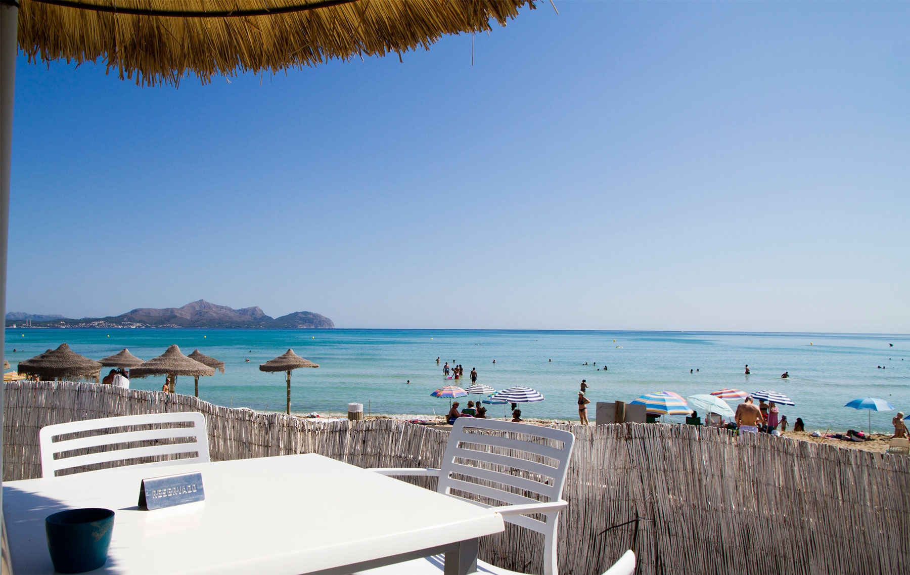 Can Gavella Mallorca: de chiringuito op het zand van Playa de Muro 7 Tafel op het terras van Can Gavella met het strand van Playa de Muro erachter