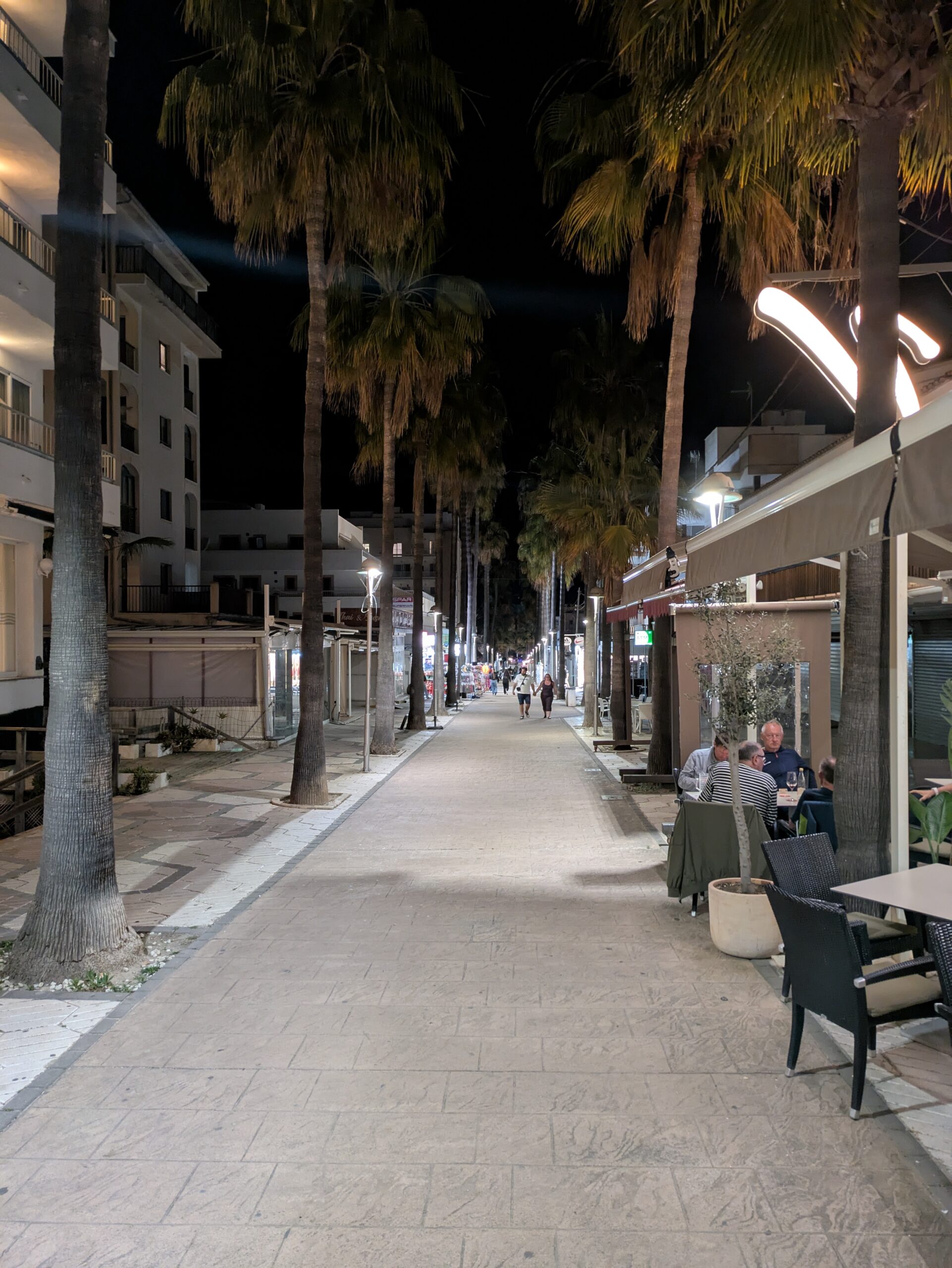Can Picafort Mallorca: stranden, boulevard en s'Albufera 2 De Avinguda Josep Trias in Can Picafort in de avond, met palmbomen en verlichte terrassen