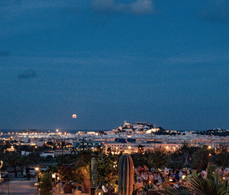 Het terras van Casa Maca bij schemering met de verlichte silhouetten van Ibiza-stad en Dalt Vila