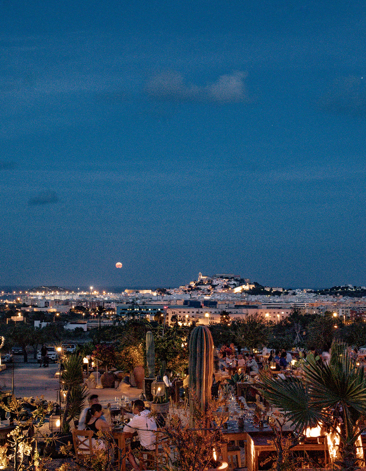 Het terras van Casa Maca bij schemering met de verlichte silhouetten van Ibiza-stad en Dalt Vila