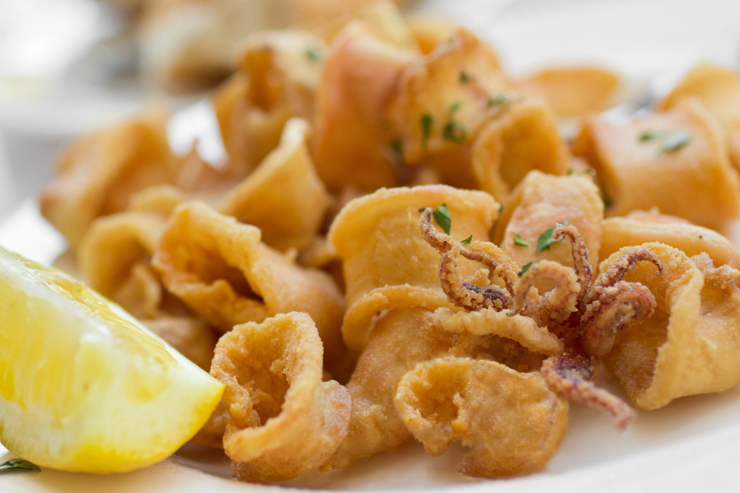 Bord met gefrituurde calamares en een partje citroen bij Cassai Beach House