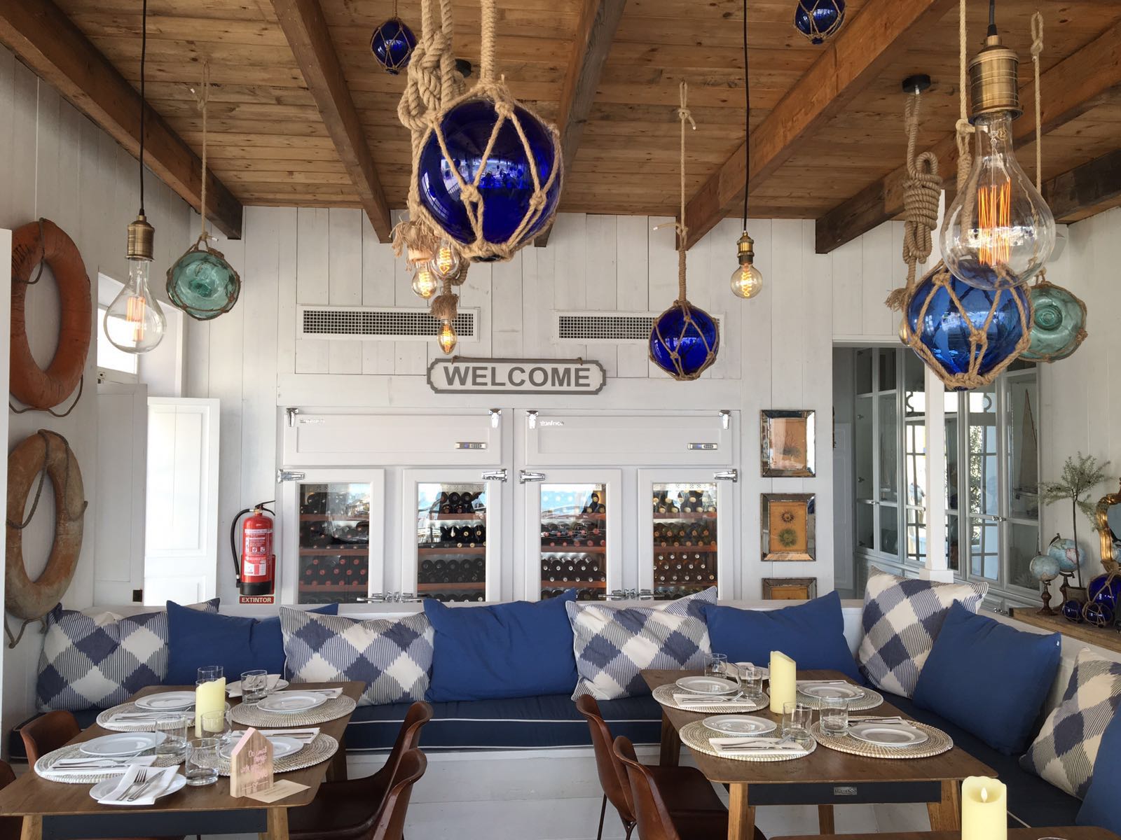 De houten eetzaal van Cassai Beach House met blauwe kussens en maritieme decoratie