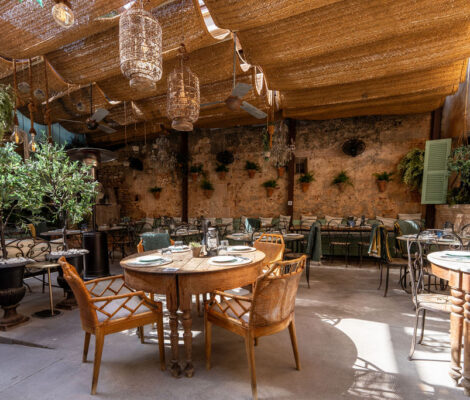 De overdekte patio met pergola, tafels en planten van Cassai Gran Café in Ses Salines