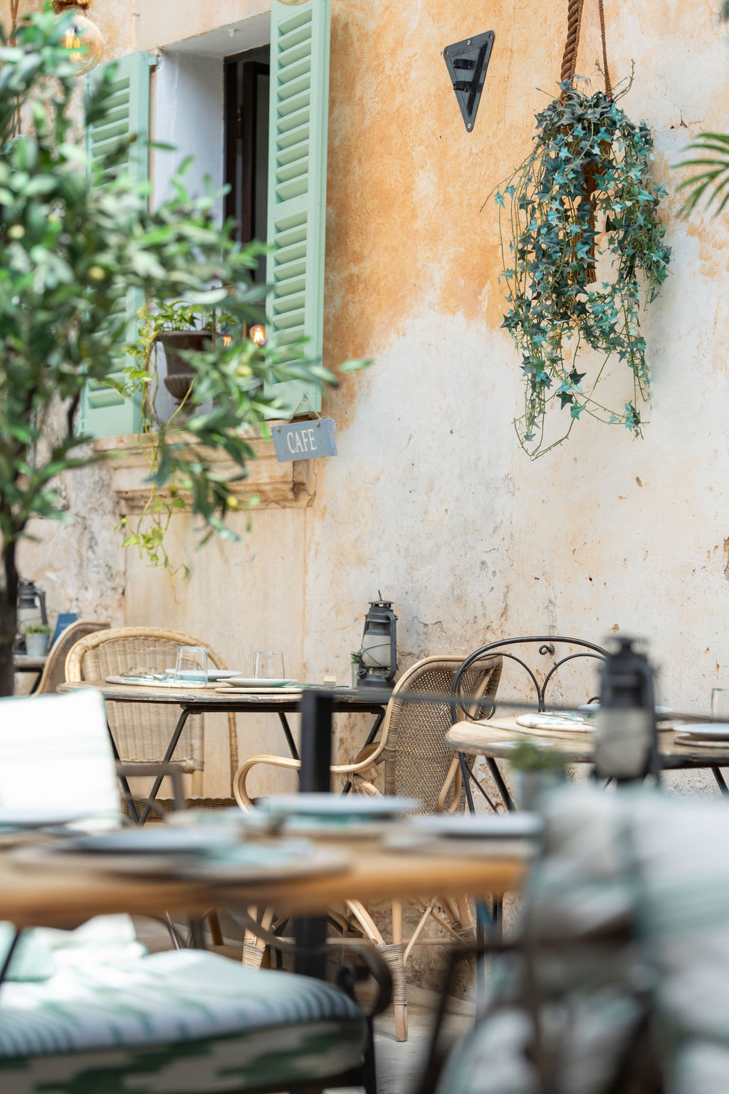 Cassai Gran Café Ses Salines: mediterraan eten in een oud dorpspand 2 Tafels op het terras van Cassai tegen een rustieke natuurstenen muur met groene luiken