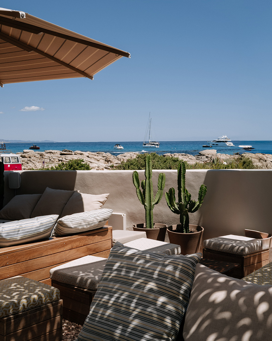 Chezz Gerdi Formentera: het iconische strandrestaurant van Es Pujols 7 Loungehoek met kussens en cactussen bij Chezz Gerdi met de zee op de achtergrond