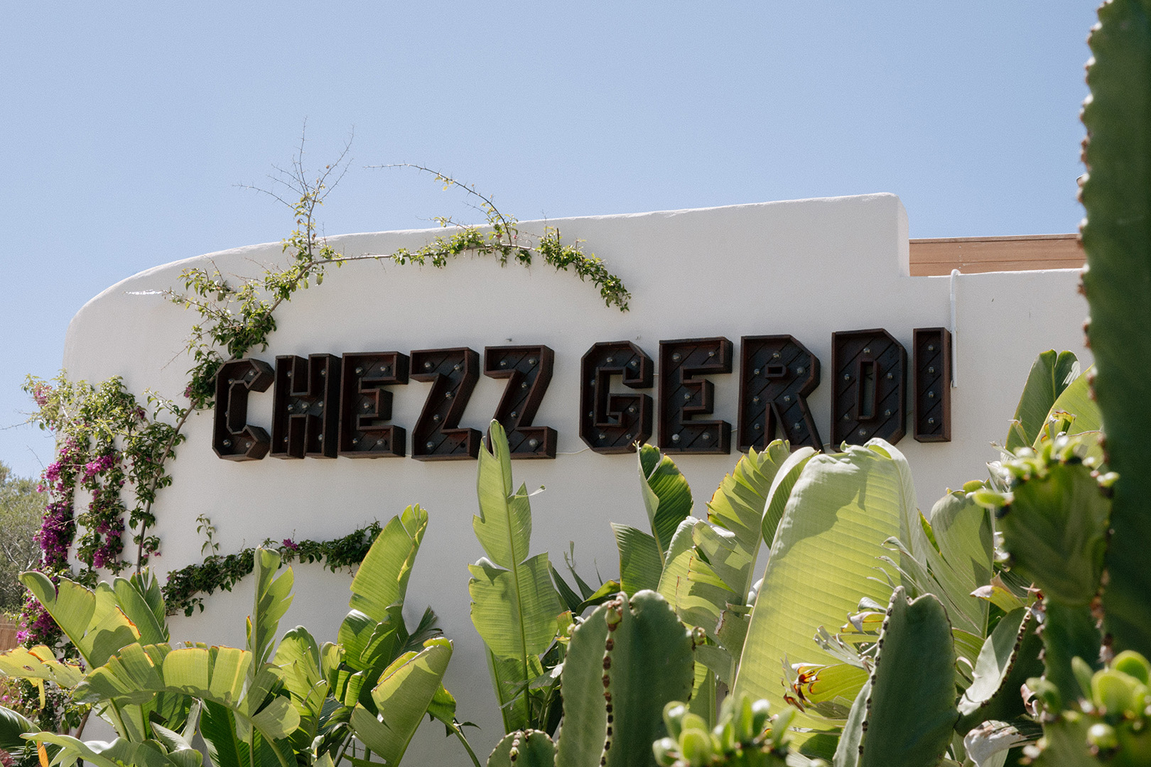 Chezz Gerdi Formentera: het iconische strandrestaurant van Es Pujols 6 Het naambord van Chezz Gerdi op een witte muur met cactussen bij de ingang