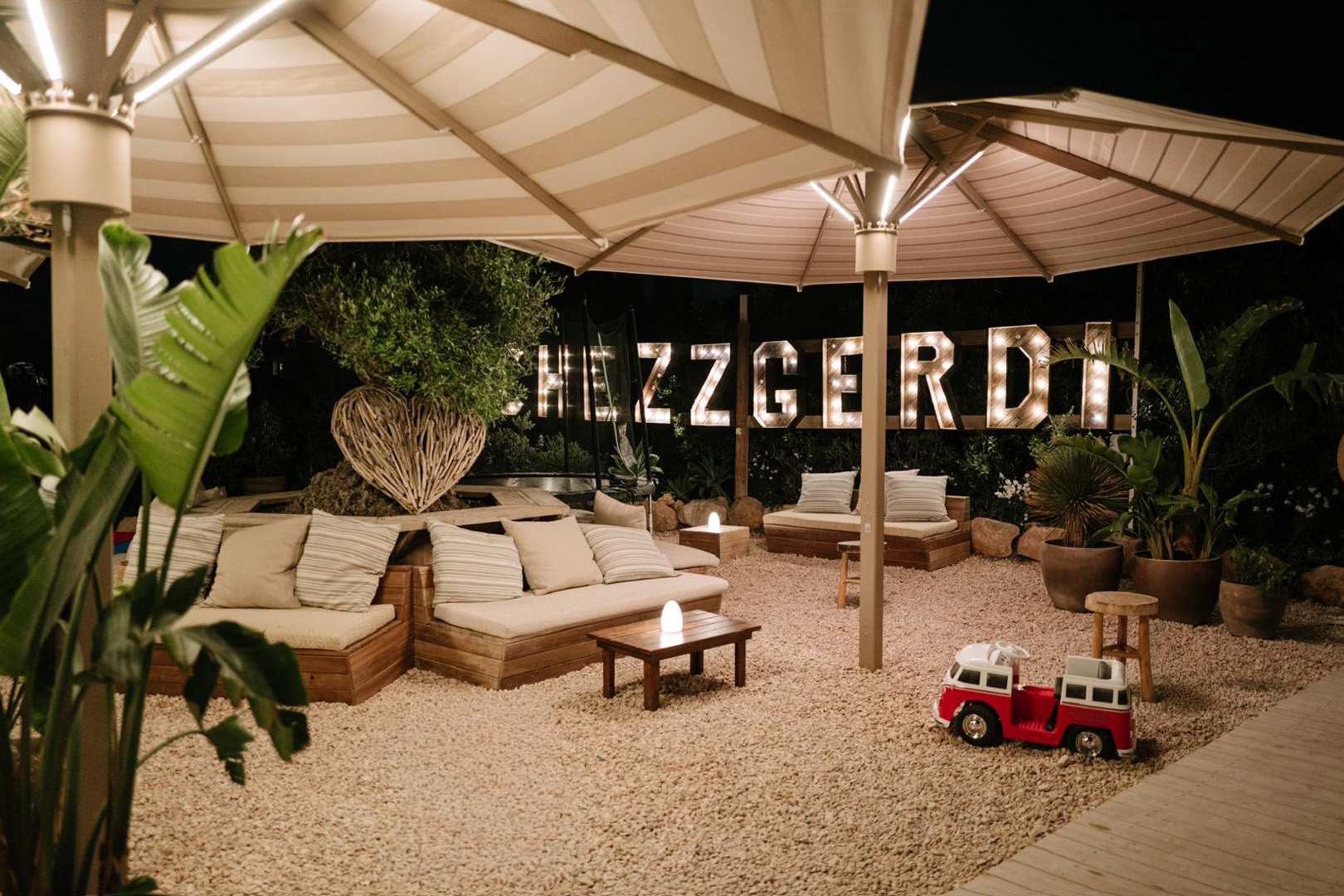 Chezz Gerdi Formentera: het iconische strandrestaurant van Es Pujols 3 Ligbedden en loungehoeken op het zand bij Chezz Gerdi, met de naam in letters op het strand