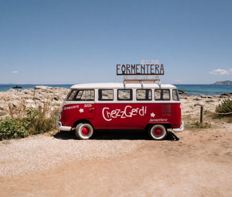 De rode Volkswagen-bus van Chezz Gerdi op het strand van Es Pujols, met Formentera op het dak