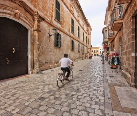 Smalle geplaveide straat in het centrum van Ciutadella op Menorca met een fietser