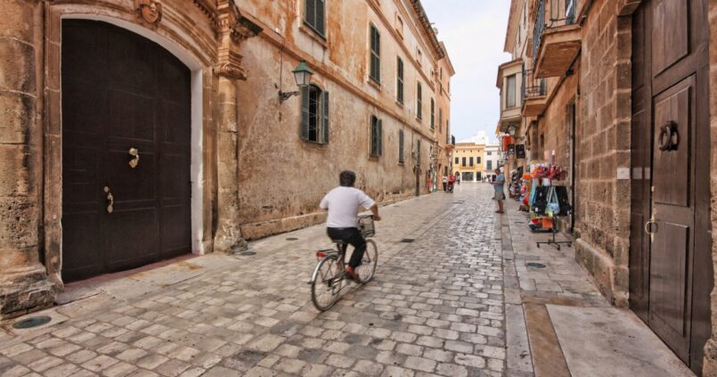 Smalle geplaveide straat in het centrum van Ciutadella op Menorca met een fietser