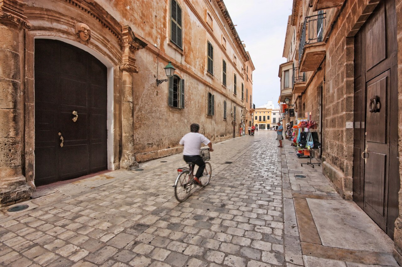 Smalle geplaveide straat in het centrum van Ciutadella op Menorca met een fietser