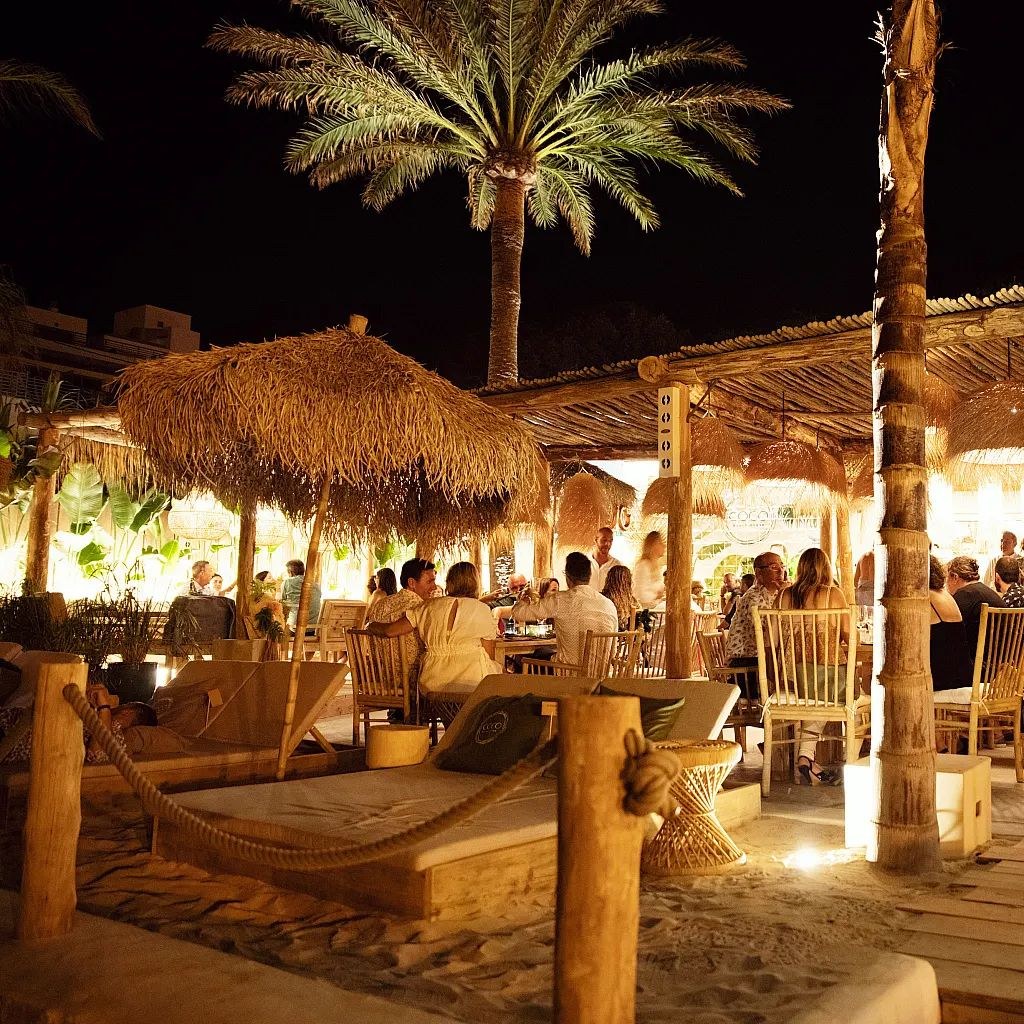 Cucum Beach House in de avond met verlichte rieten parasols en sfeerlicht