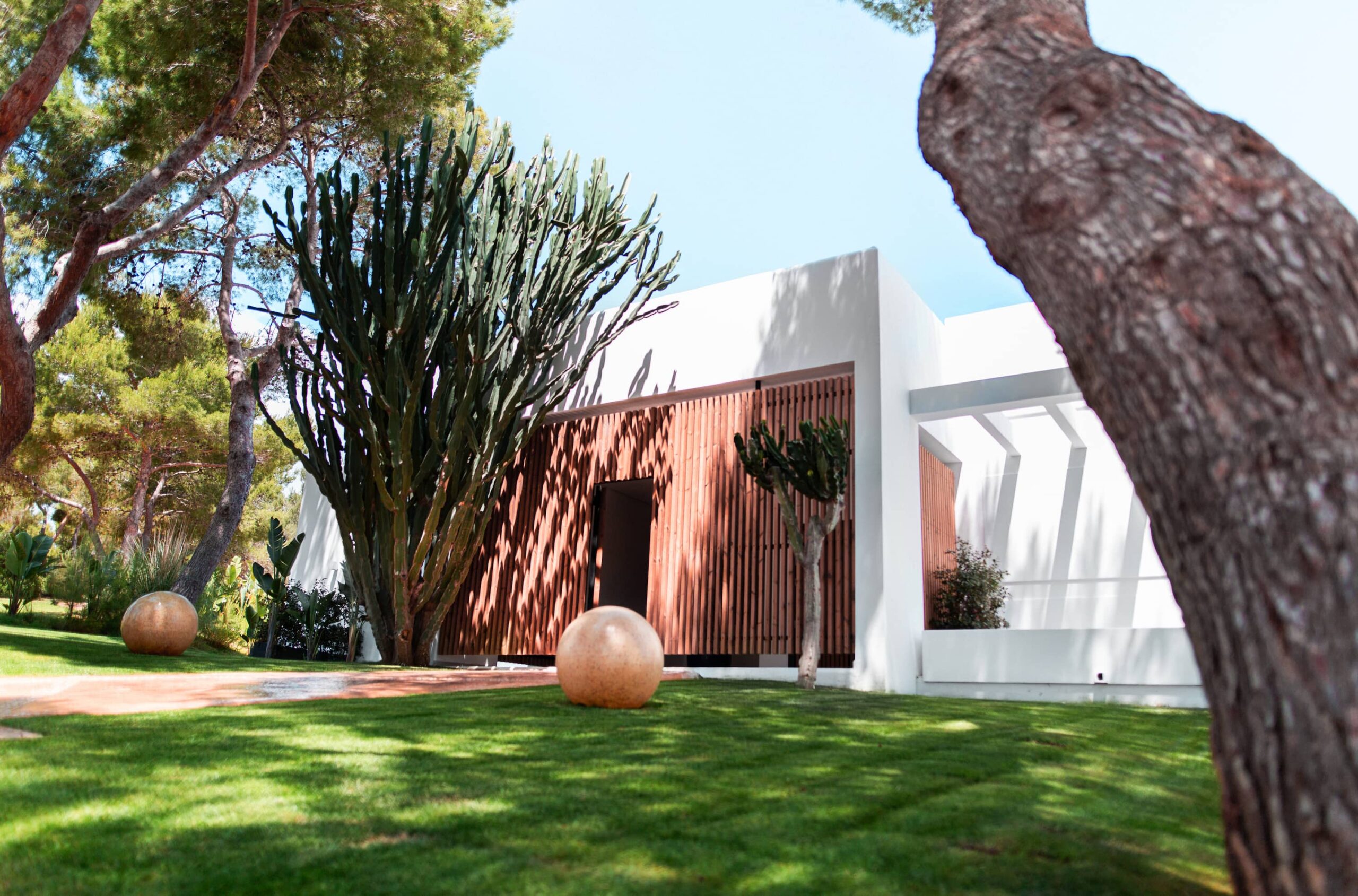 Destino Ibiza: van Destino Pacha naar Destino Five, en wat er veranderde 10 Het witte gebouw van Destino met de tuin en een pijnboom