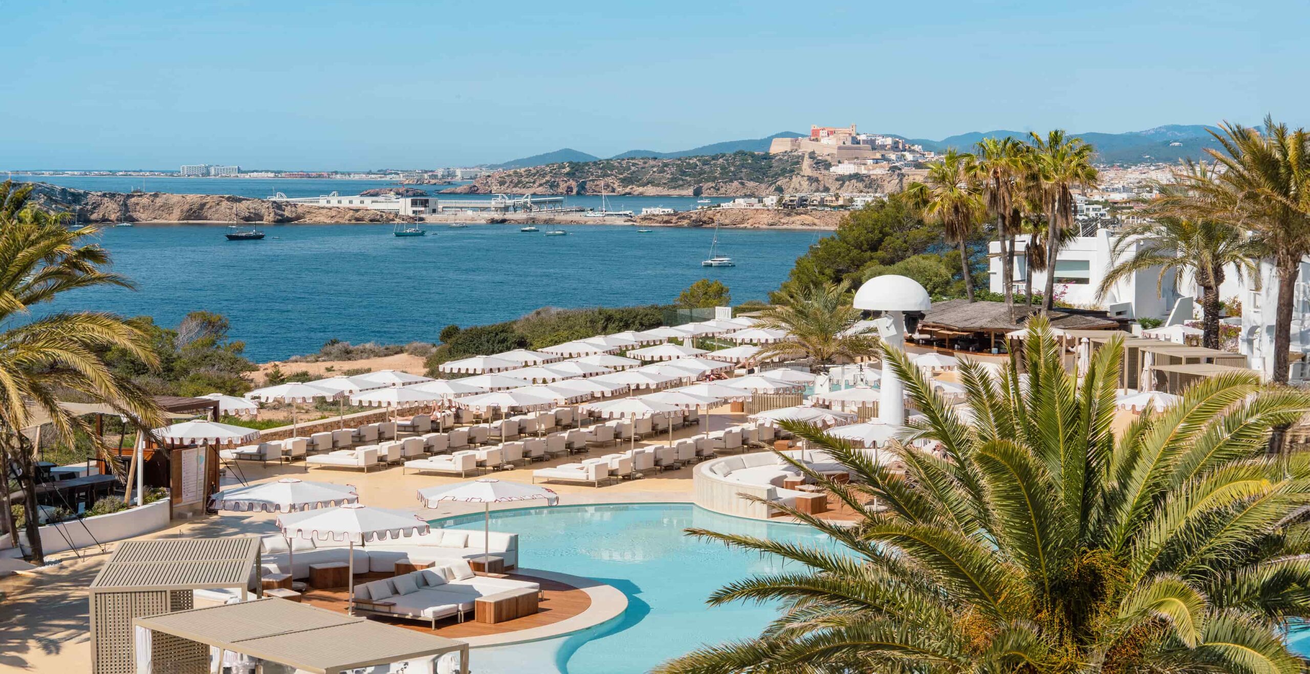 Destino Ibiza: van Destino Pacha naar Destino Five, en wat er veranderde 4 Uitzicht vanaf Destino over de baai naar Dalt Vila, met het zwembad en de ligbedden