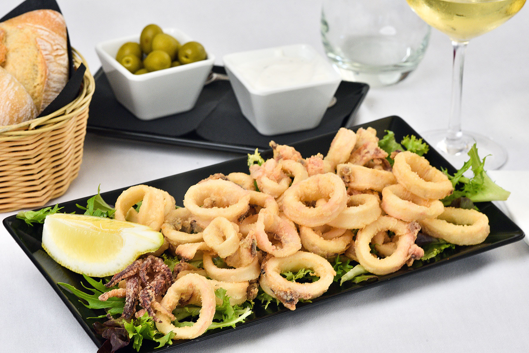 Bord met gefrituurde calamares, olijven en witte wijn bij El Mirador