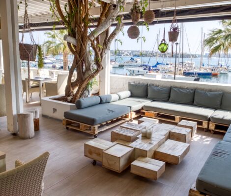 Het loungeterras van El Rais onder een pergola met uitzicht op de jachthaven van Maó