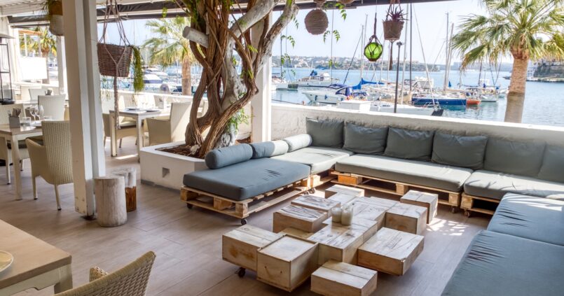 Het loungeterras van El Rais onder een pergola met uitzicht op de jachthaven van Maó
