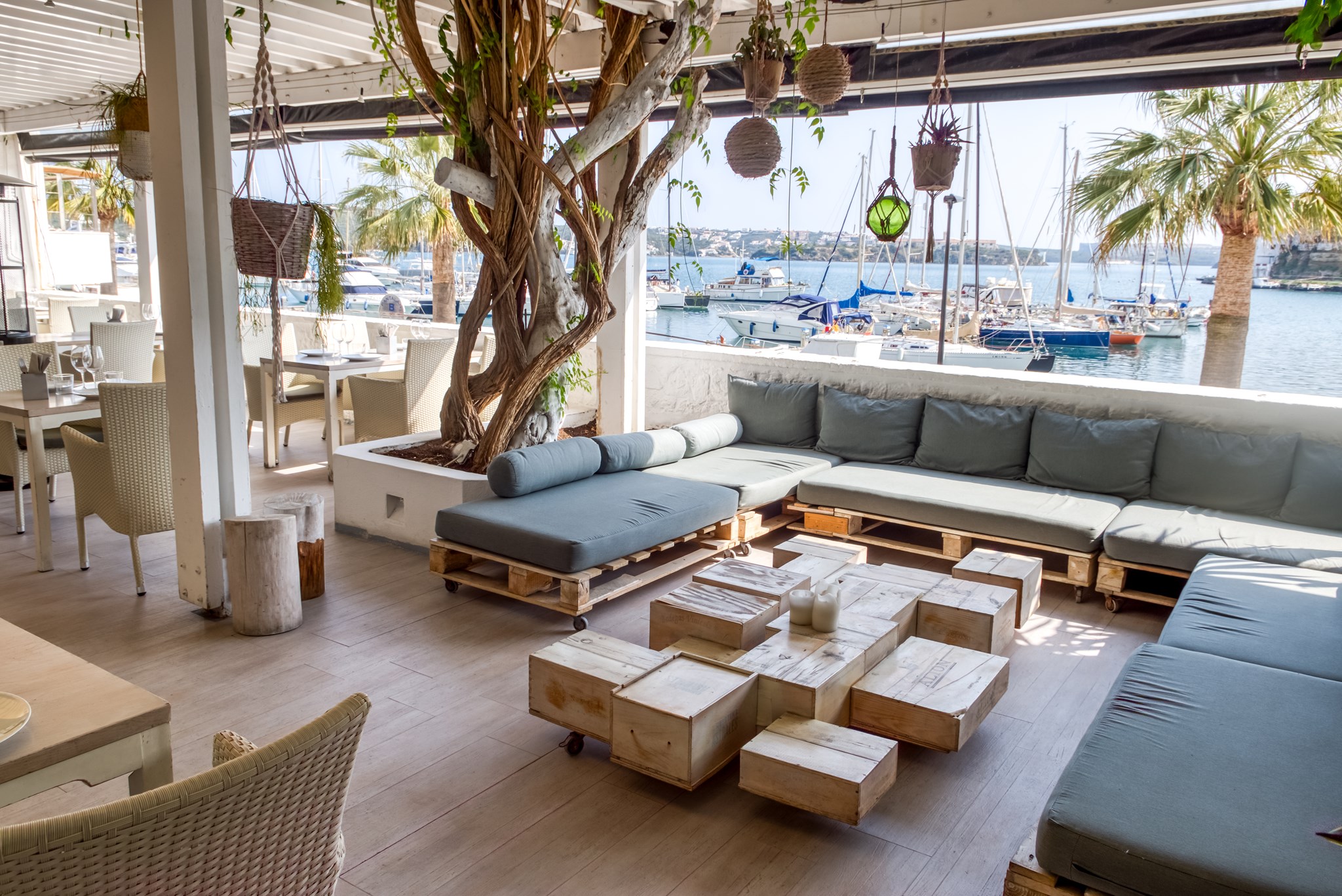 Het loungeterras van El Rais onder een pergola met uitzicht op de jachthaven van Maó