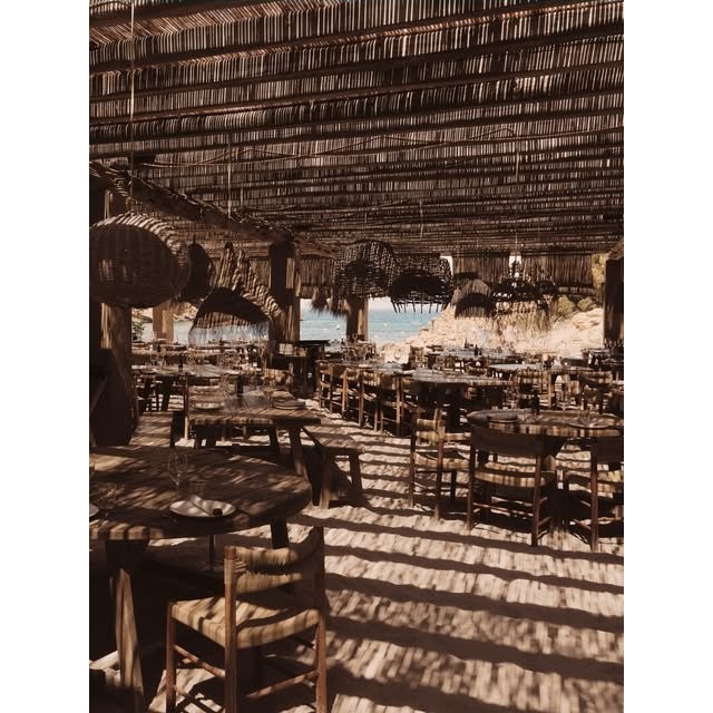 Rijen tafels onder een rieten dak bij El Silencio Ibiza