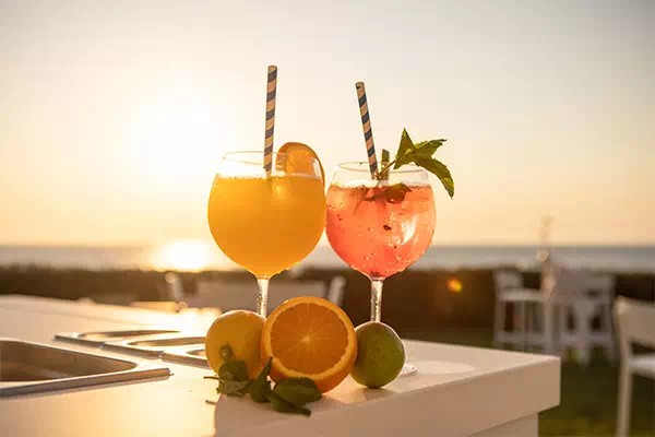 Twee cocktails van Eolo Sunset Bar met de zee en de zonsondergang op de achtergrond