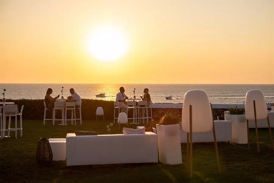 Het loungeterras van Eolo Sunset Bar op de klif met de zonsondergang boven zee