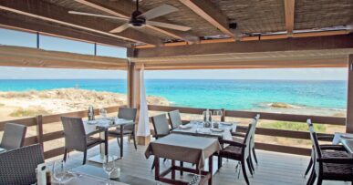 Restaurante Es Caló Formentera: verse vis aan het haventje van Sant Agustí 14 Het overdekte terras met gedekte tafels van Restaurante Es Caló boven de turquoise zee op Formentera