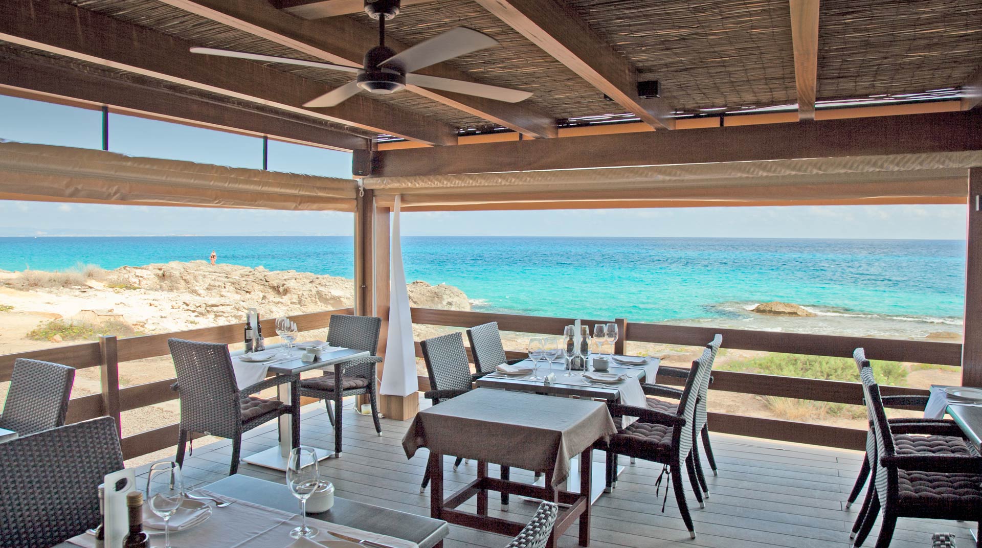 Restaurante Es Caló Formentera: verse vis aan het haventje van Sant Agustí 1 Het overdekte terras met gedekte tafels van Restaurante Es Caló boven de turquoise zee op Formentera