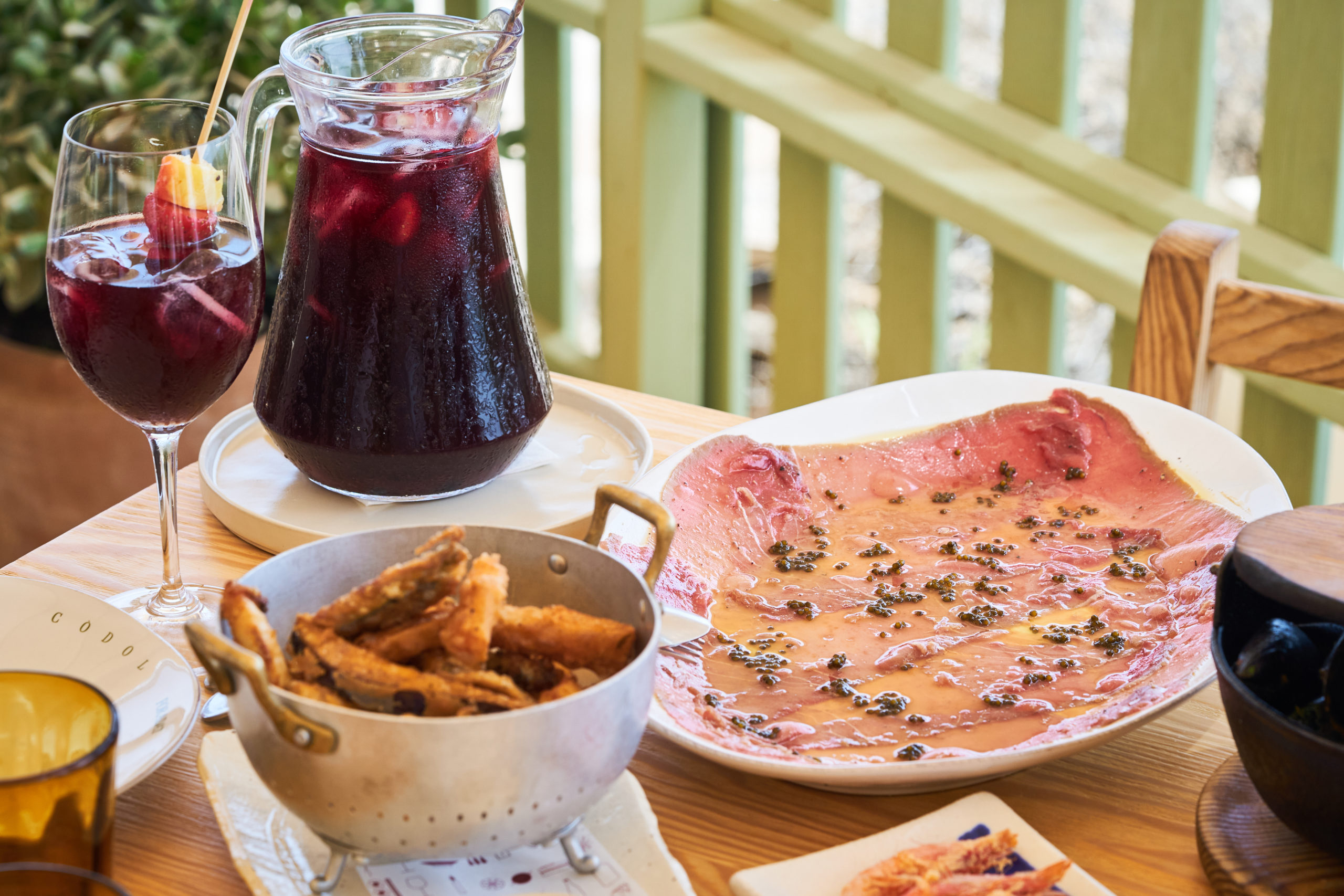 Gedekte tafel bij Es Còdol Foradat met een kan sangria, gefrituurde vis en viscarpaccio