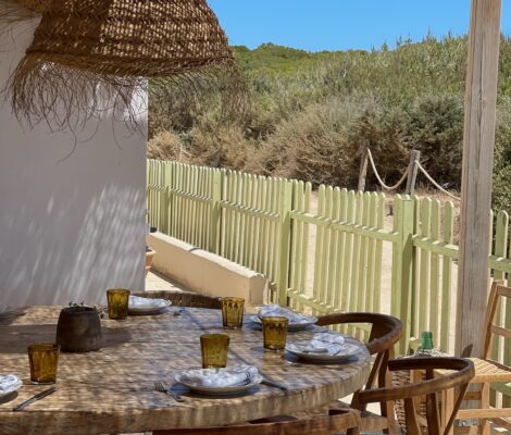 Het terras van Es Còdol Foradat met gedekte tafels onder een dak van zeegras aan Platja de Migjorn