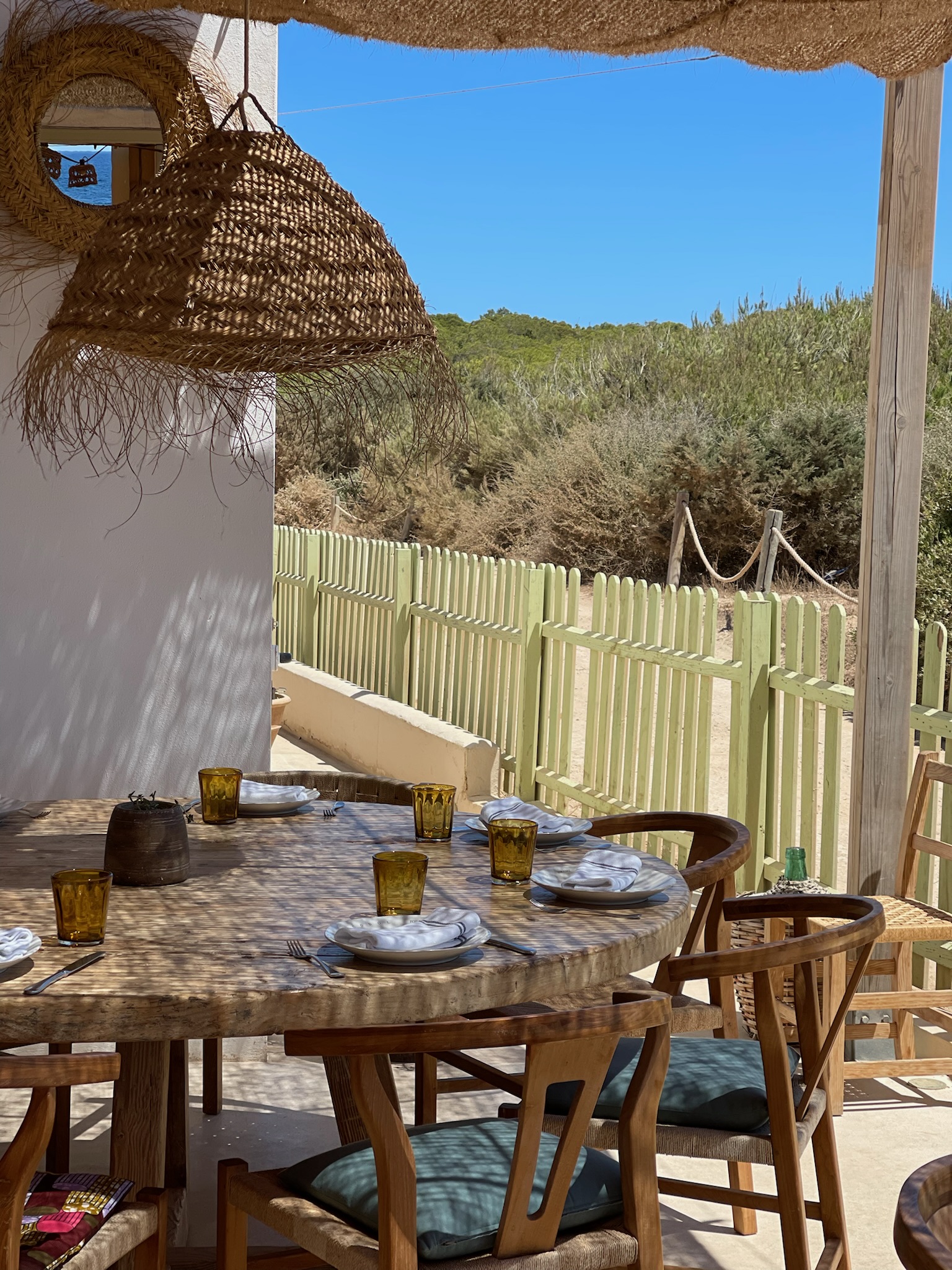 Het terras van Es Còdol Foradat met gedekte tafels onder een dak van zeegras aan Platja de Migjorn