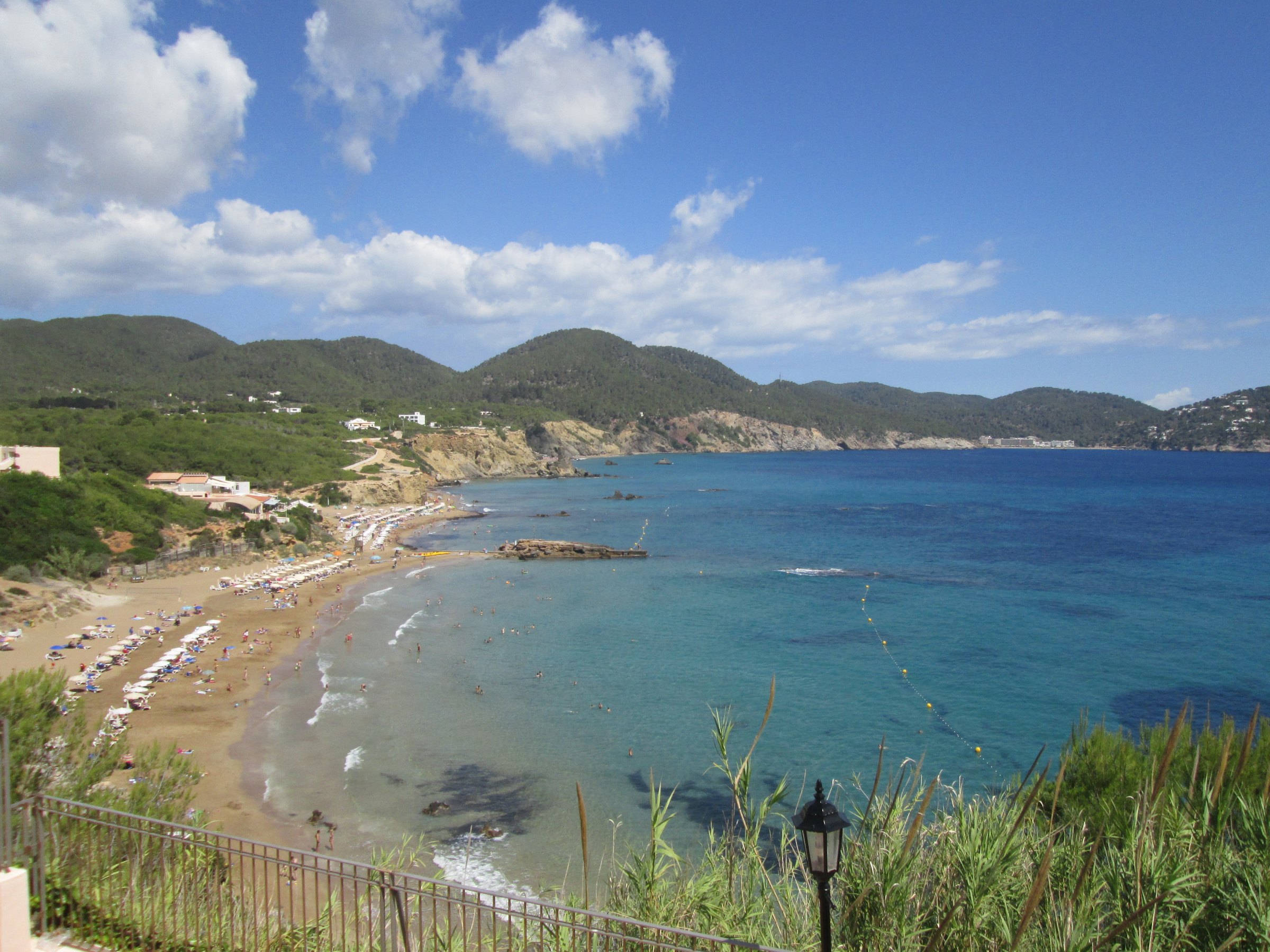 Het strand van Es Figueral van bovenaf gezien, met Aigües Blanques en de noordoostkust van Ibiza op de achtergrond