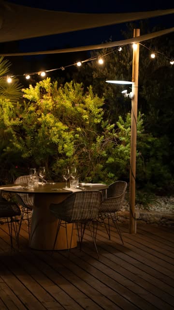 Het verlichte terras van Es Mal Pas in de avond met lichtjes tussen de bomen