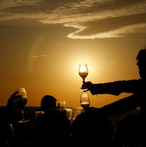 Geheven wijnglazen tegen de ondergaande zon op het terras van Es Molí de Sal