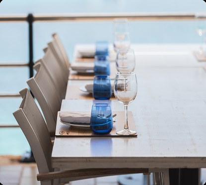 Gedekte tafel met blauwe glazen op het terras van Es Raor aan zee