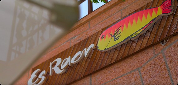 Het naambord van Es Raor met de raor-vis op de muur van het vissershuis