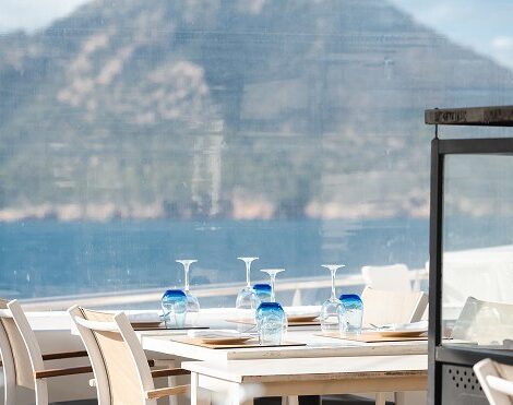 Het terras van Es Raor in Sant Elm met gedekte tafels en uitzicht over zee naar de bergen