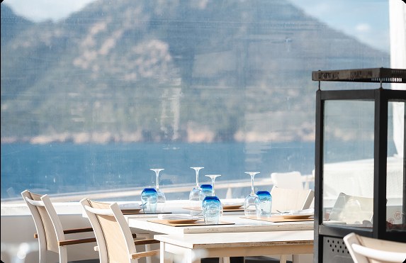 Het terras van Es Raor in Sant Elm met gedekte tafels en uitzicht over zee naar de bergen
