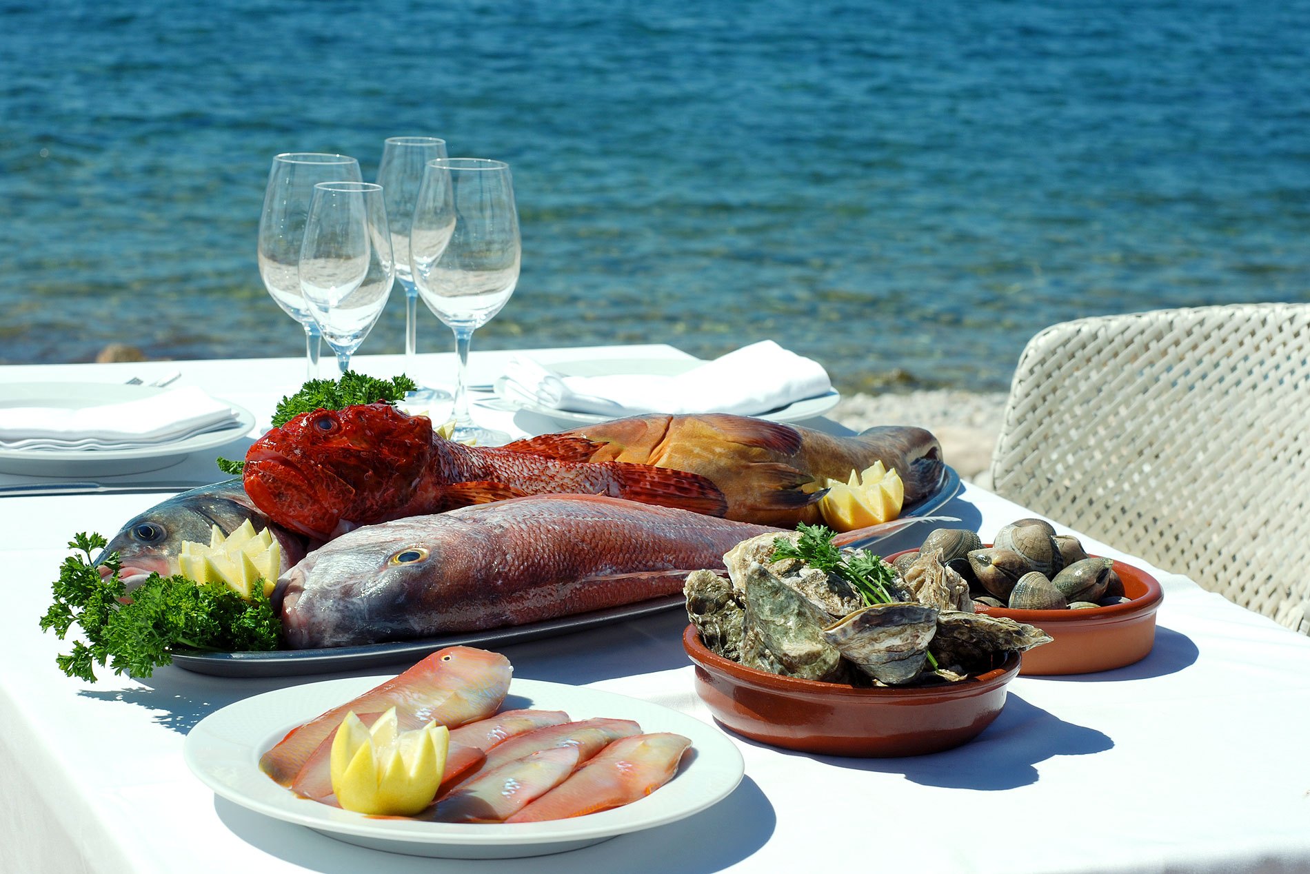 Es Torrent Ibiza: verborgen kiezelstrand in Porroig met topvis-restaurant 2 Verse vis en schelpdieren op een tafel aan zee bij Restaurante Es Torrent, Ibiza