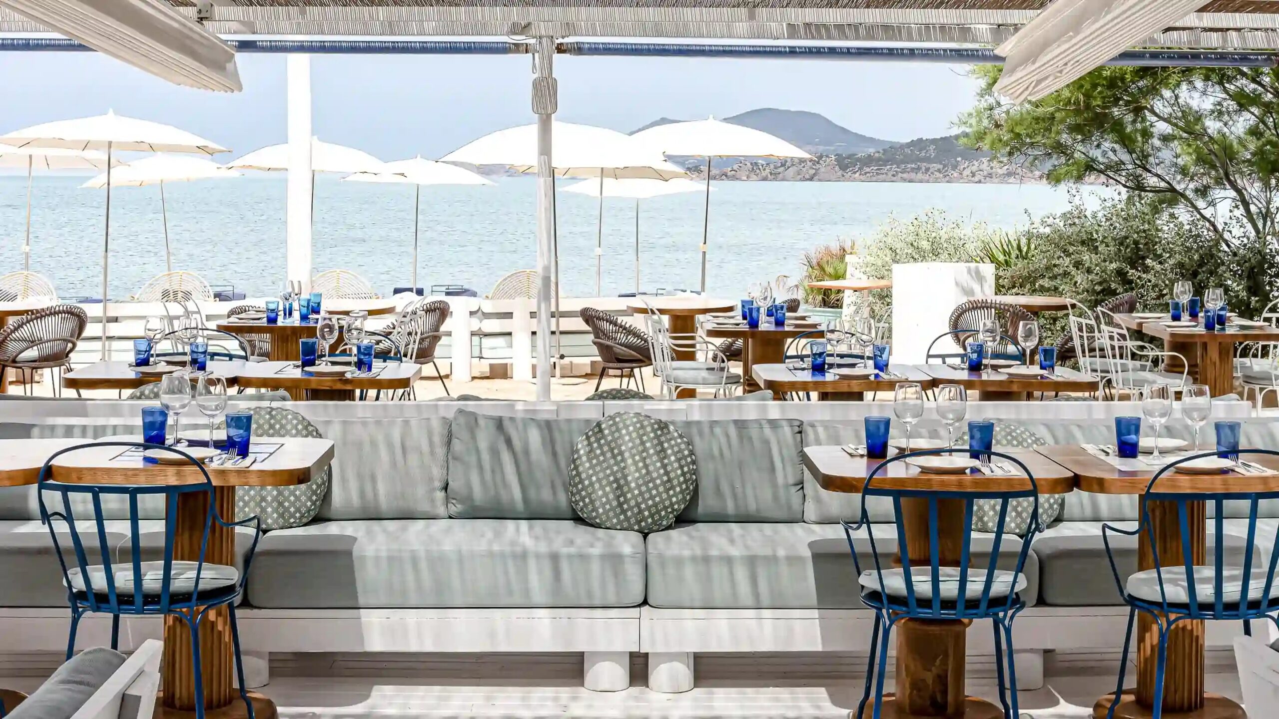 Het terras van Experimental Beach Ibiza met witte parasols en uitzicht over zee