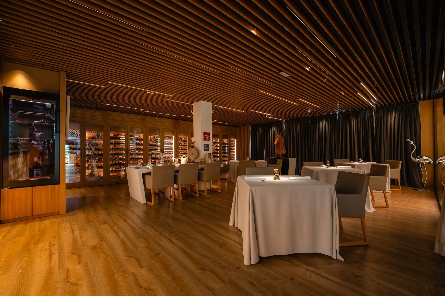 De eetzaal van sterrenrestaurant Fusion19 in Playa de Muro op Mallorca, met houten lattenplafond en gedekte tafels