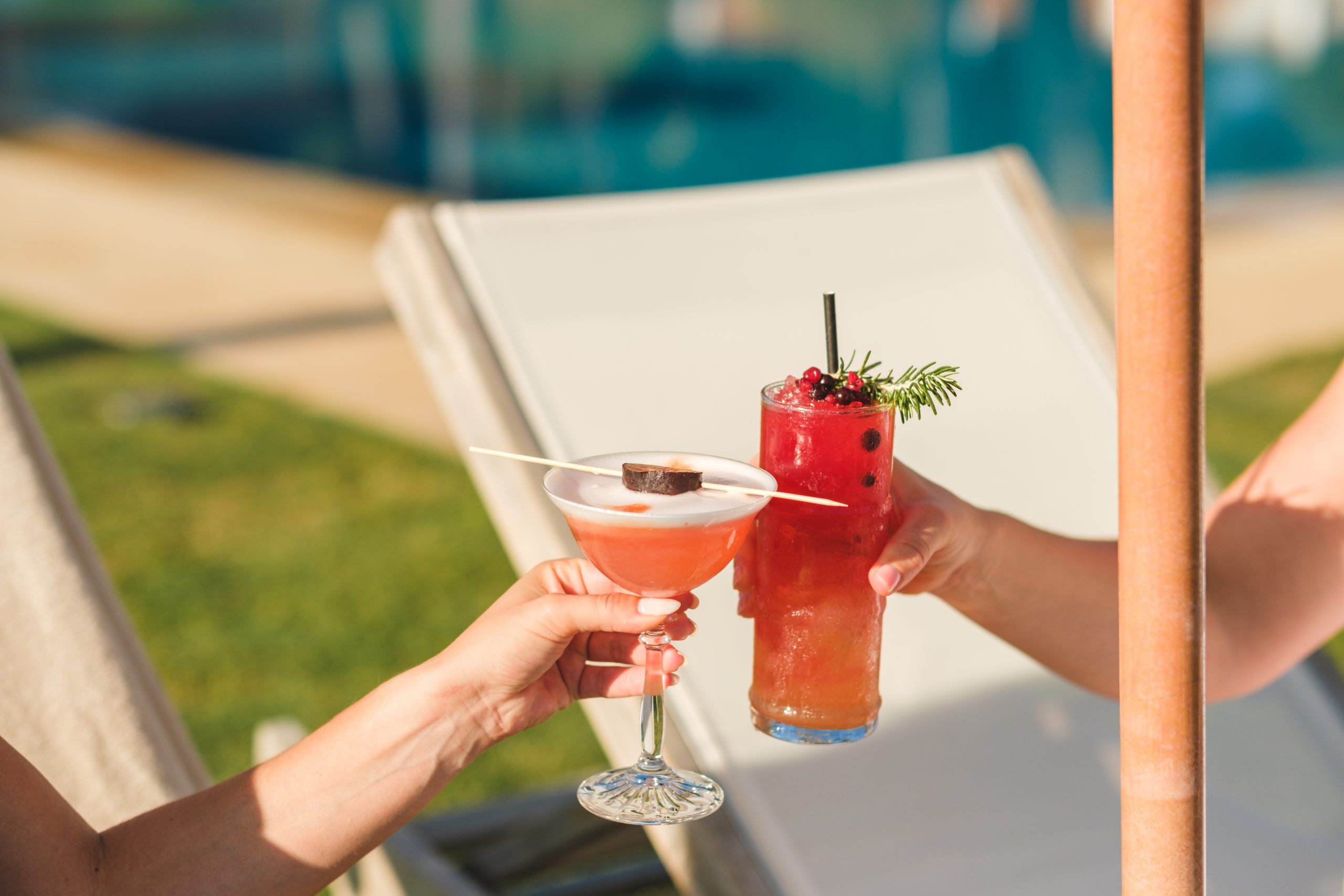 Twee cocktails geproost bij het zwembad van Gecko Beach Club